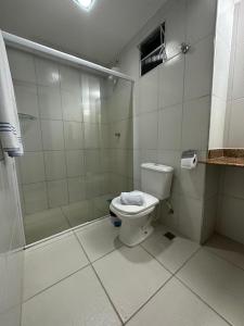 um banheiro branco com vaso sanitário e chuveiro em Fragata Hotel em Guarapari
