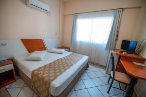 um quarto com uma cama, uma escrivaninha e uma janela em Fragata Hotel em Guarapari mais 37 fotografias