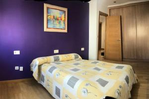 a bedroom with a bed and a purple wall at Toxiños in Carballino
