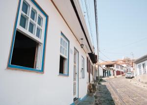 a white building with blue windows on a street at Hospedagem Rancho Fundo in Diamantina