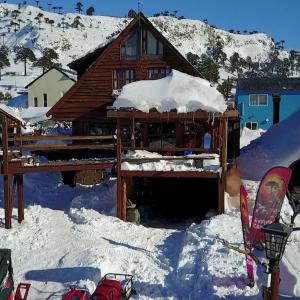 a log cabin in the snow with a snowboard at el refugio de caniche in Caviahue