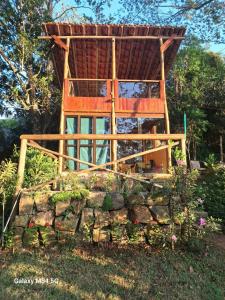 a tree house with a roof on top of a stone wall at Chopana Alpina na Praia Brava in Ubatuba