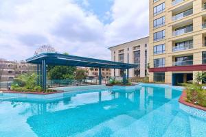 a large swimming pool with a blue canopy in front of a building at Kilimani Premier 1BR in Nairobi