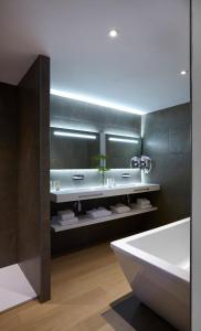 La salle de bains est pourvue d'une baignoire blanche, d'un lavabo et d'une baignoire. dans l'établissement Hôtel In Situ, à Béziers