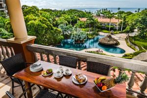 a table with food on a balcony with a view of a pool at El Diria 302- 2 Bedroom Ocean View Condo in Tamarindo