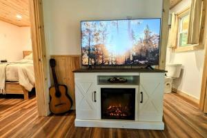 a living room with a tv and a fireplace at River Retreat Cabin - Living Water Farm in Cleveland