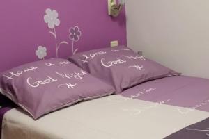 a purple bed with two pillows with writing on it at Appartement centre-ville - gîte urbain avec jardin in Bastogne