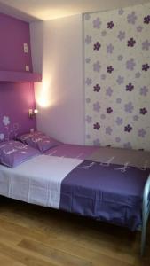 a bedroom with a bed with purple sheets and a wall at Appartement centre-ville - gîte urbain avec jardin in Bastogne