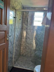 una ducha con puerta de cristal en un baño en Pé na areia Beach House, en Fundão