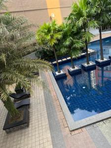 a swimming pool with palm trees in a building at Mi Casa - Cozy Studio with FREE access to Fitness Centre, swimming pool and stunning City View located near the CBD of Ortigas, Makati, BGC in Manila
