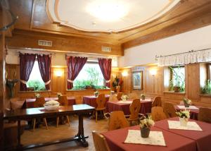 un comedor con mesas, sillas y ventanas en Hotel Garnì Il Cirmolo, en Rocca Pietore