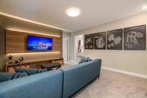 Una sala de estar con un sofá azul y un televisor de pantalla plana. en 7988 Magical 5BD Home Perfect Disney Retreat, en Kissimmee