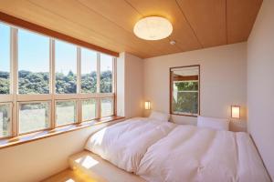 Un dormitorio con una cama grande en una habitación con ventanas. en プライベートリゾート南風, en Higashiizu