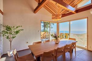 Un comedor con mesa y sillas y ventanas. en プライベートリゾート南風, en Higashiizu