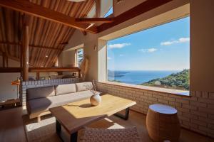 Una sala de estar con un sofá y una mesa y una ventana grande. en プライベートリゾート南風, en Higashiizu