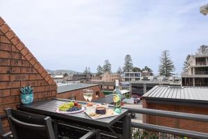 a table with a plate of food and wine on a balcony at Joy's Hideaway in Terrigal