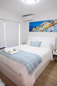 a bedroom with a white bed with a painting on the wall at Joy's Hideaway in Terrigal