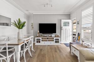a living room with a television and a dining room table at Spa & Chill Lodge in Budgewoi