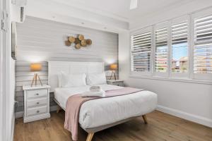 a white bedroom with a bed and a window at Spa & Chill Lodge in Budgewoi +23 photos