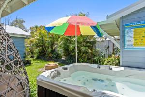 a hot tub with a colorful umbrella in a yard at Spa & Chill Lodge in Budgewoi