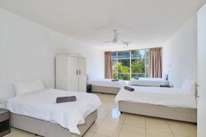 a white room with two beds and a window at Inn & Out Sandton Park in Johannesburg