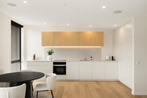 a kitchen with white cabinets and a table and chairs at WARNING Extreme views 4 bed 3 bath luxury in Queenstown