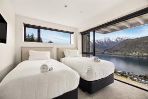 two beds in a room with a large window at WARNING Extreme views 4 bed 3 bath luxury in Queenstown