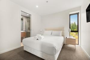 a white bedroom with a white bed and a window at WARNING Extreme views 4 bed 3 bath luxury in Queenstown