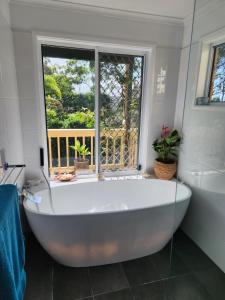 a large white bath tub in a bathroom with a window at Bushland View Retreat in Ocean Shores +10 photos
