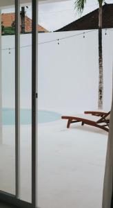 una puerta corredera de cristal que conduce a un patio con banco en La Bianca Studio Apartment, en Dalung