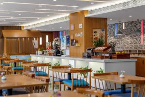 a restaurant with wooden tables and chairs and a counter at Holiday Inn Express Chengdu Airport Zone Free shuttle from Shuangliu International Airport to hotel ,welcome drink in Chengdu