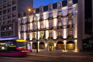 un bus passant devant un grand bâtiment la nuit dans l'établissement Oceania Le Jura Dijon, à Dijon