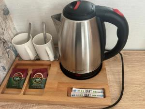 a coffee pot and cups on a wooden tray at Amal Hotel in Astana