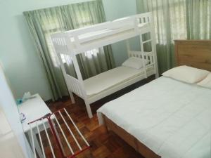 a bedroom with a white bunk bed next to a window at Pet-Friendly, Spacious Family Cottage, with Games Lounge & Near Beach in Port Dickson