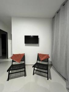 2 Stühle neben einer Wand mit einem TV in der Unterkunft Departamento Ejecutivo cerca de BJX in Santa Gertrudis