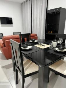 einem schwarzen Esstisch mit Stühlen und einem Sofa in der Unterkunft Departamento Ejecutivo cerca de BJX in Santa Gertrudis