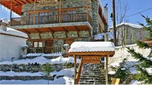 una casa grande con nieve en la parte delantera en Ta Skalopatia, en Palaios Agios Athanasios