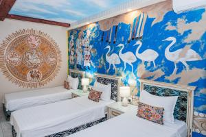 two beds in a room with a mural of birds at Gur Emir Palace boutique hotel in Samarkand