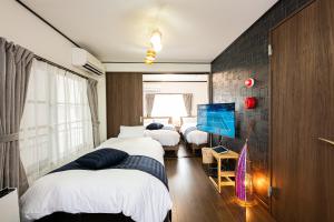 a bedroom with three beds and a tv on a wall at Vacation Rental NISHIDA in Kagoshima +31 photos