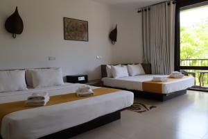 two beds in a hotel room with towels on them at Handagedara Resort & Spa in Mirissa