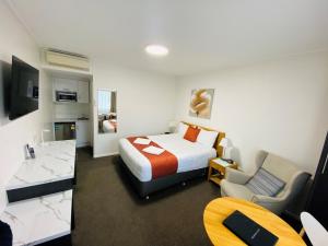 a hotel room with a bed and a chair at Colonial Lodge Motor Inn in Yass