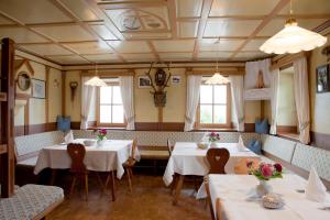 un restaurante con 2 mesas, sillas y ventanas en Lienharterhof, en Monguelfo-Tesido