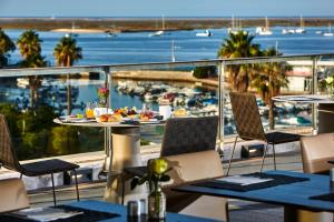 a balcony with tables and chairs and a view of a harbor at Hotel Faro & Beach Club in Faro