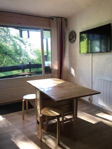 einen Holztisch und Stühle in einem Zimmer mit Fenster in der Unterkunft T2 Rez-de-chaussée terrasse et table extérieure in Enchastrayes