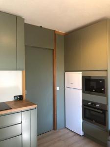 eine Küche mit einem weißen Kühlschrank und einer Mikrowelle in der Unterkunft T2 Rez-de-chaussée terrasse et table extérieure in Enchastrayes