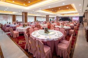 深圳Shenzhen Jincheng Hotel的摆放着白色桌椅的大型宴会厅
