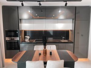 a kitchen with a wooden table and white chairs at Sky Suites-KASS Towers in Okponglo