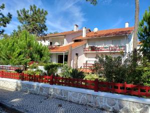 a house with a red fence in front of it at Hotel Verde Pinho Bed&Breakfast in São Pedro de Moel