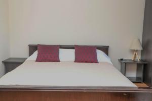 een bed met twee rode kussens erop bij Андреева къща in Zlatograd