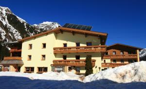 ein Gebäude mit einem Sonnendach im Schnee in der Unterkunft Köflerhof Appartements in Sankt Leonhard im Pitztal